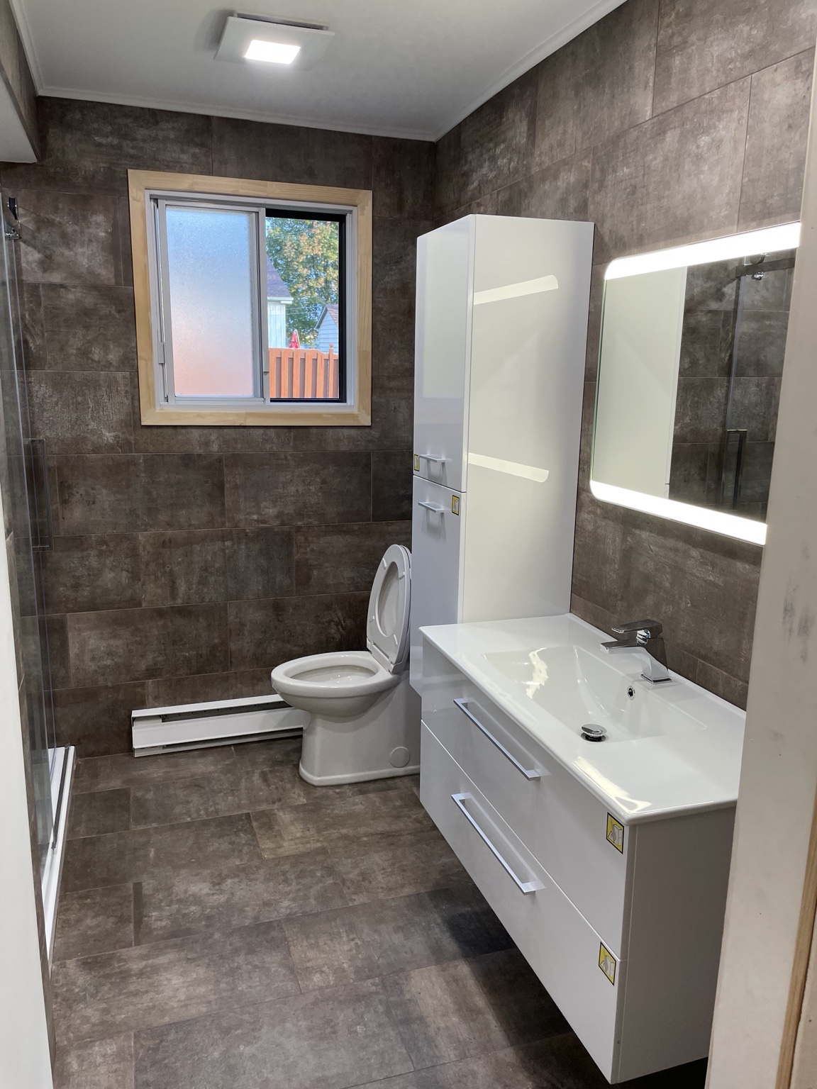 Bathroom after renovation with modern brown tile and white vanity